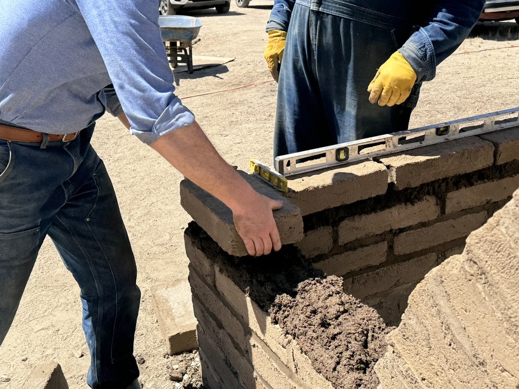 Adobe block wall under construction during a natural building workshop