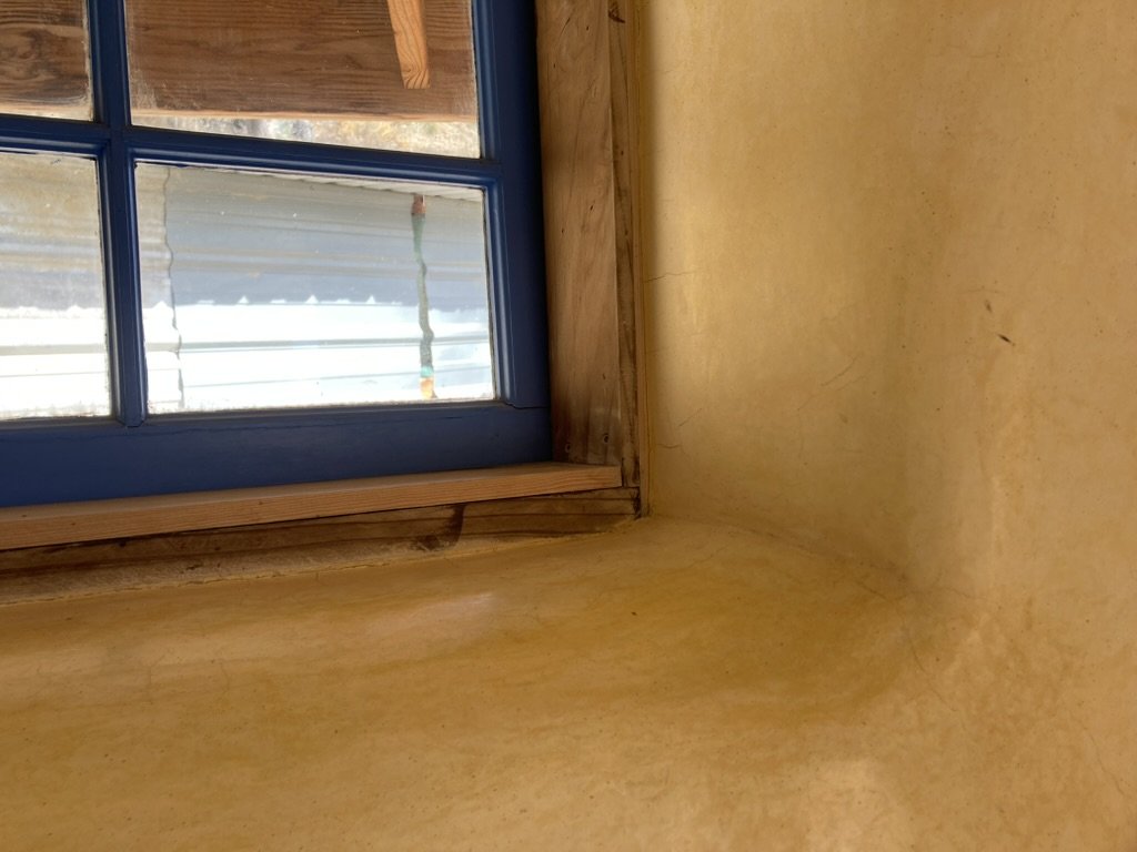 Natural plaster finish around a window in a natural building